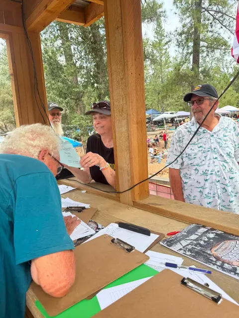 A person writing at a registration counter while volunteers assist.