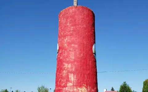 A tall red structure stands against a clear blue sky.