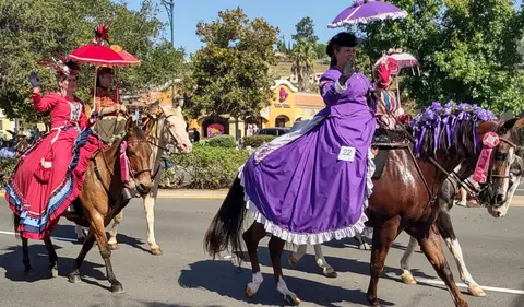 Costumed participants ride horses in a parade.