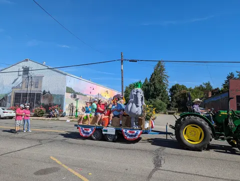 A tractor pulls a decorated parade float along a street.