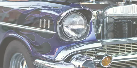 A close-up view of a purple vintage car with flames painted on the side.