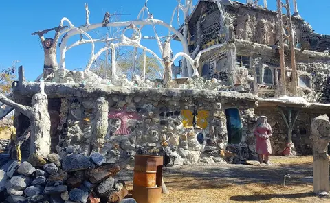 An eclectic exterior structure built with stones, cement, and whimsical sculptures.