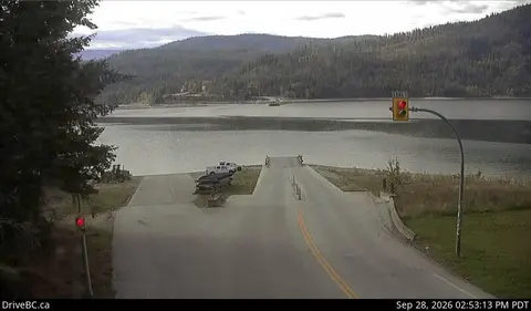 A view of a ferry terminal leading to a body of water with hills in the background.