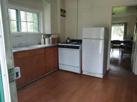 An interior view of a kitchen with wooden cabinets, a white stove, and a white refrigerator.