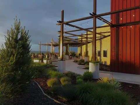 An outdoor patio area next to a building with metal siding at sunset.