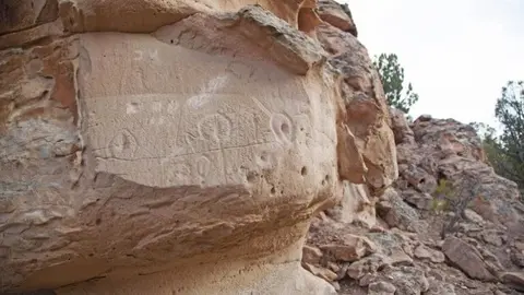 Petroglyphs carved into the surface of a rock formation outdoors.