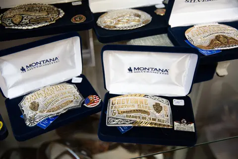An array of engraved silver belt buckles in display boxes.