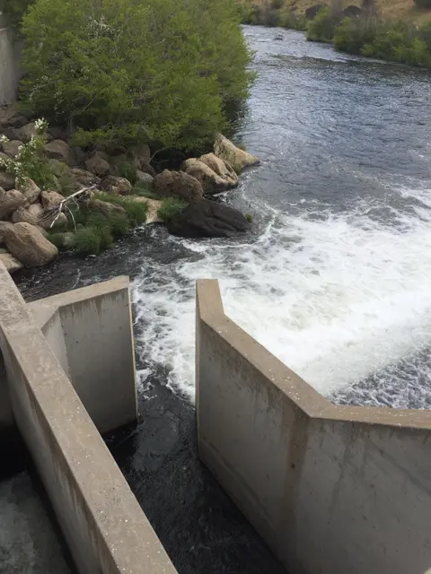 Water flowing through a concrete spillway into a river.