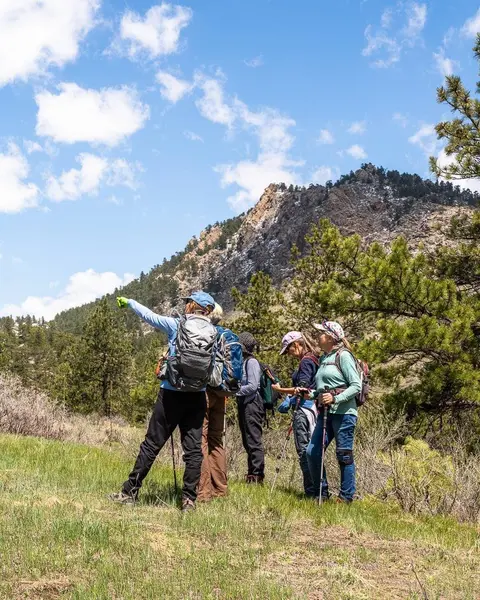 A group of hikers point toward a mountain landscape.