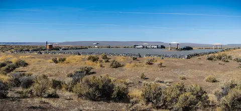 A parking lot with stone walls in a desert landscape under a clear blue sky.