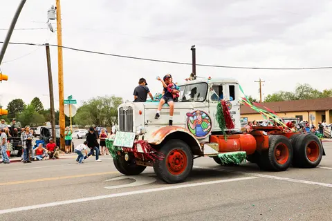 A decorated old truck in a parade on a street.