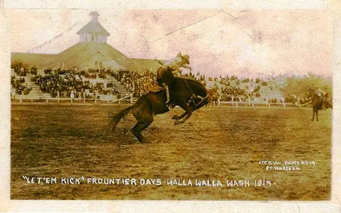 Historic photo of a rodeo event with a cowboy riding a bucking horse.