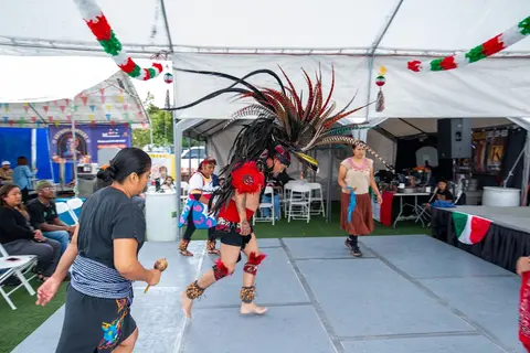 Performers in traditional attire dancing on a stage under a tent.