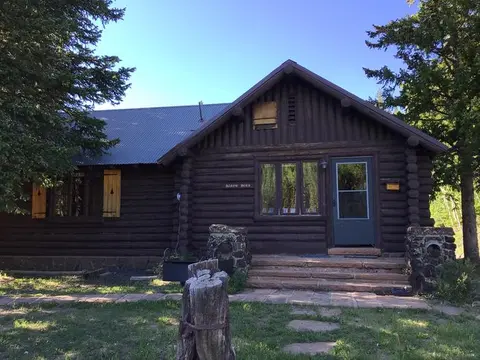 An exterior view of a brown log cabin surrounded by trees.