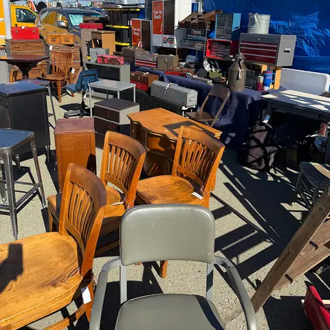 An outdoor flea market display with various used furniture and household goods.