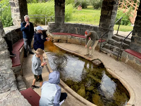 People gather around a stone spring inside a shelter.