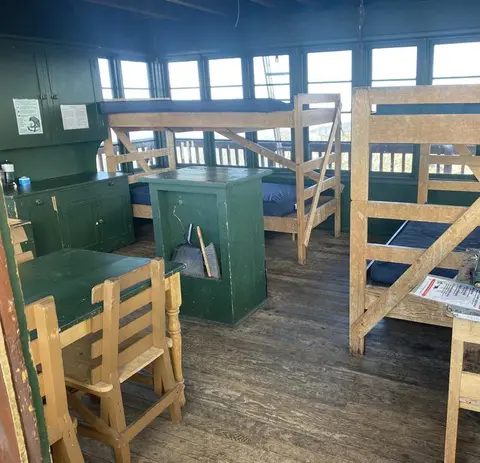 An interior view of a room with wooden bunk beds, green cabinets, and a table.