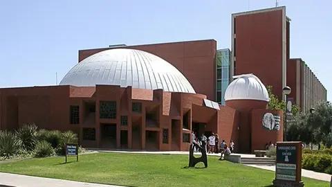 Exterior view of a brick science building featuring a large dome and an adjacent observatory dome.