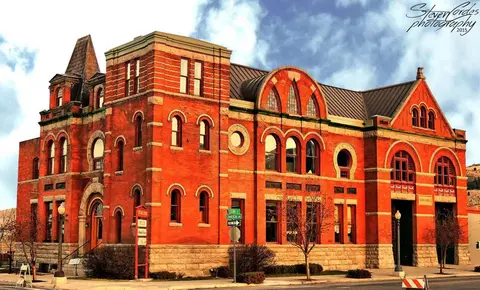 A large historic red brick building with arched windows and stone foundation.