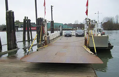 A small ferry carrying cars docked at a pier.