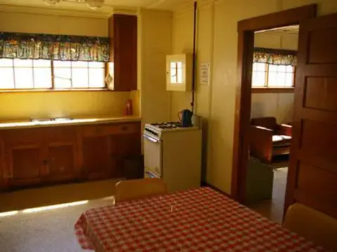 An interior view of a kitchen with wooden cabinets and a checkered tablecloth.