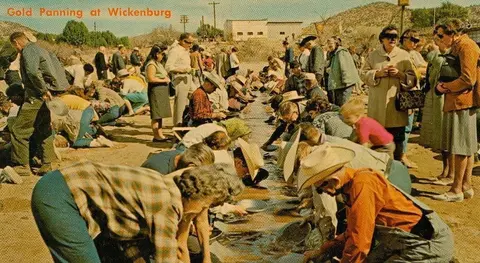 A vintage postcard showing people gold panning outdoors.