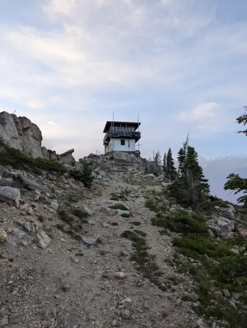 A fire lookout tower sits atop a rocky mountain peak.