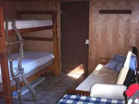 An interior view of a rustic room featuring a bunk bed and a couch.