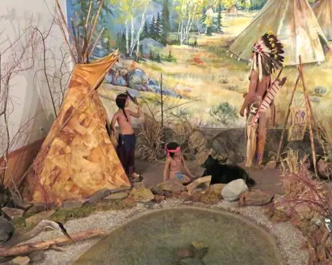 A museum diorama featuring figures, tipis, and a painted backdrop.