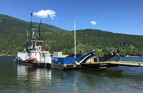 A ferry boat on a lake with green hills in the background.