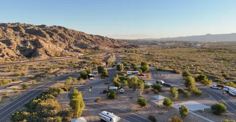 An aerial view of an RV park set in a desert landscape with mountains in the background.