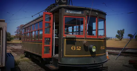 An old passenger tram sits on tracks outdoors.