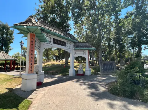 An outdoor view of an ornate arched entrance gate structure in a park.