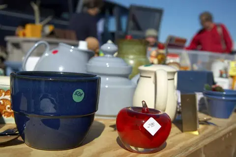 A table displays various items for sale at an outdoor market.