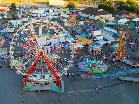 An aerial view of a carnival with a large Ferris wheel and various amusement rides.