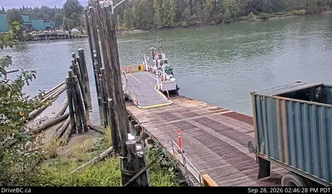 A ferry is docked at a wooden ramp next to the water.