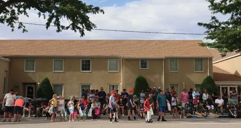 A crowd of people gathering along a street in front of a building.