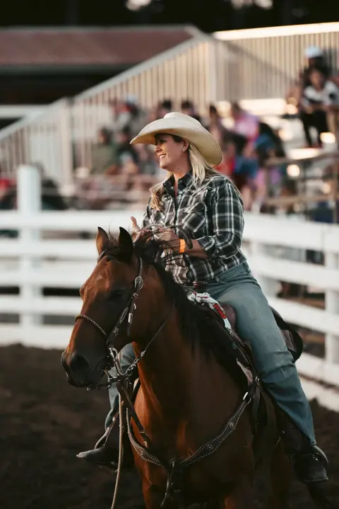 A woman rides a horse in an arena.