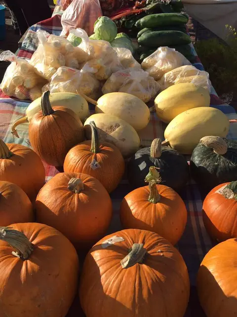 A display of pumpkins and produce at a market stall.