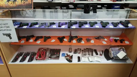 A display case showing various handguns and accessories in a store.