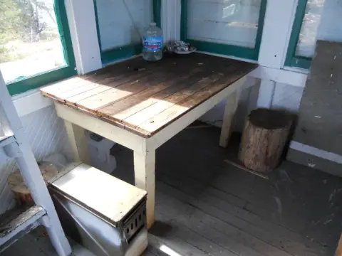 A rustic wooden table inside a small porch.