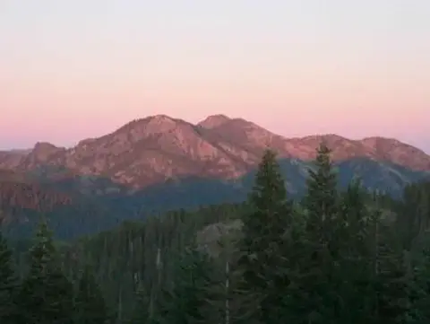 A view of mountains and forest at sunset.