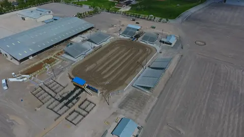 An aerial view of an outdoor rodeo arena and surrounding fairgrounds facilities.
