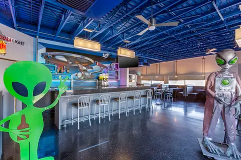 An interior view of an alien-themed restaurant or bar with a blue ceiling.