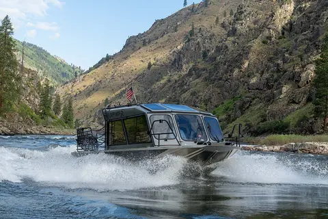 A boat navigates a river through a mountainous landscape.