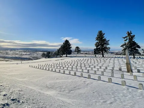A snow-covered cemetery on a hilltop under a clear blue sky.