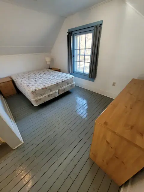 A bedroom with a mattress on the floor and wooden furniture.