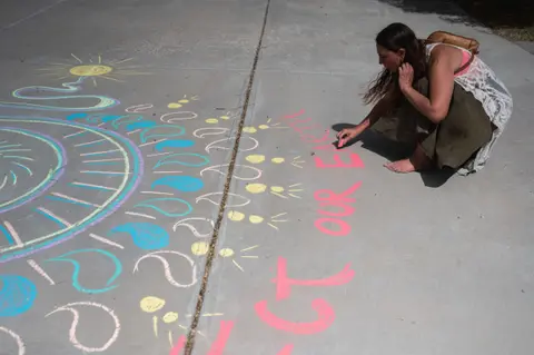 A person draws colorful chalk art on a concrete surface.