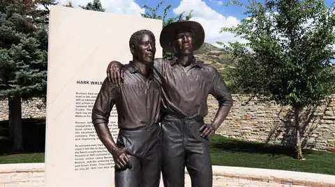 A bronze monument of two men standing together outside.