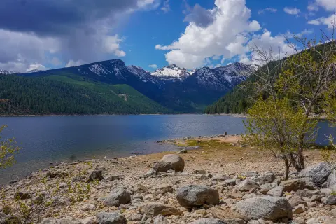 A scenic lake view with mountains in the background under a partly cloudy sky.